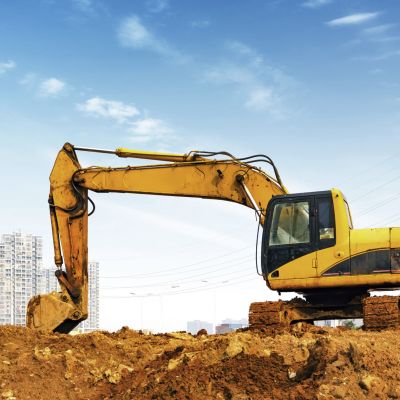 Yellow excavator on a construction site against blue sky