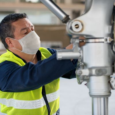 Mechanic fixing an airplane while wearing a facemask