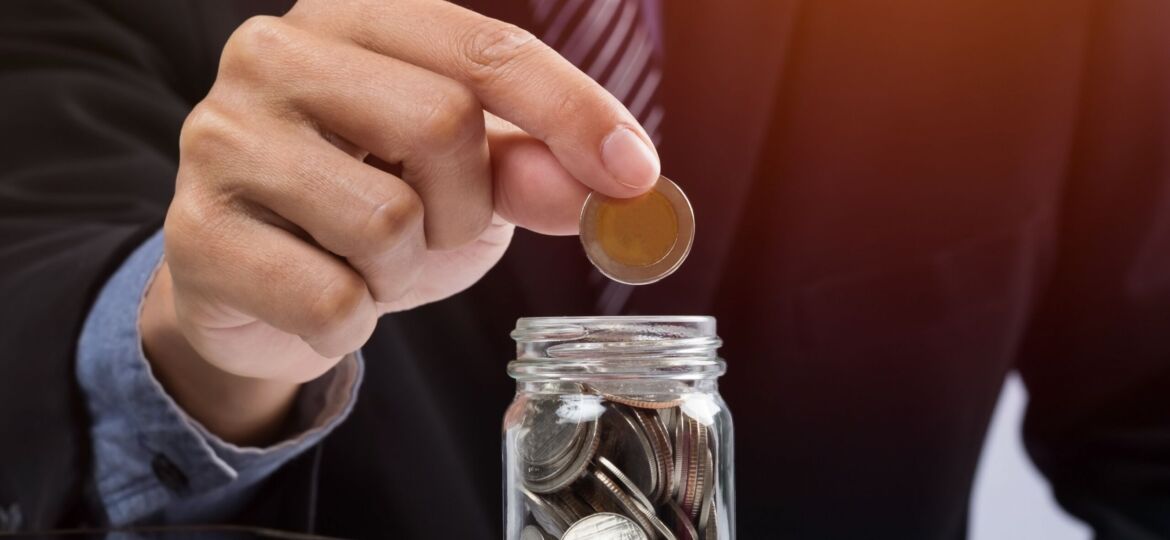 Hand putting mix coins and seed in clear bottle and copyspace, B