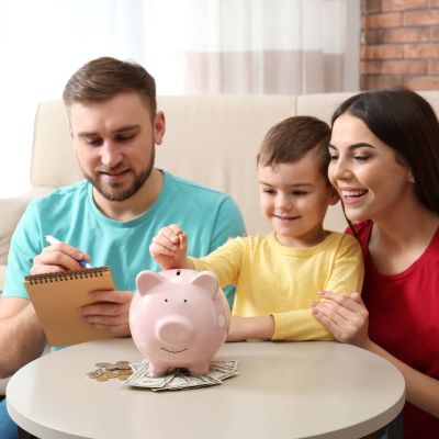 Happy,Family,With,Piggy,Bank,And,Money,At,Home