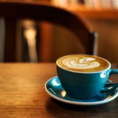 Coffee,In,Blue,Cup,On,Wooden,Table,In,Cafe,With